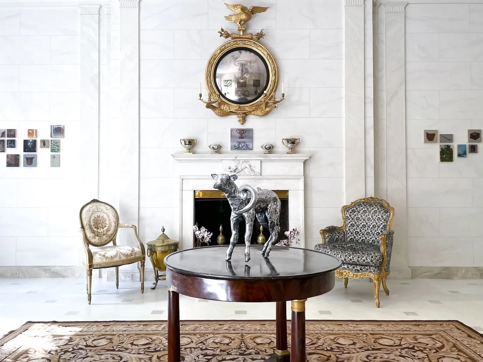 Aluminum lamb sculpture installed on new classical kitchen table next to two armchairs and fireplace in White marble interior with rug, Lei de jong, the brant foundation, impulse magazine interview.