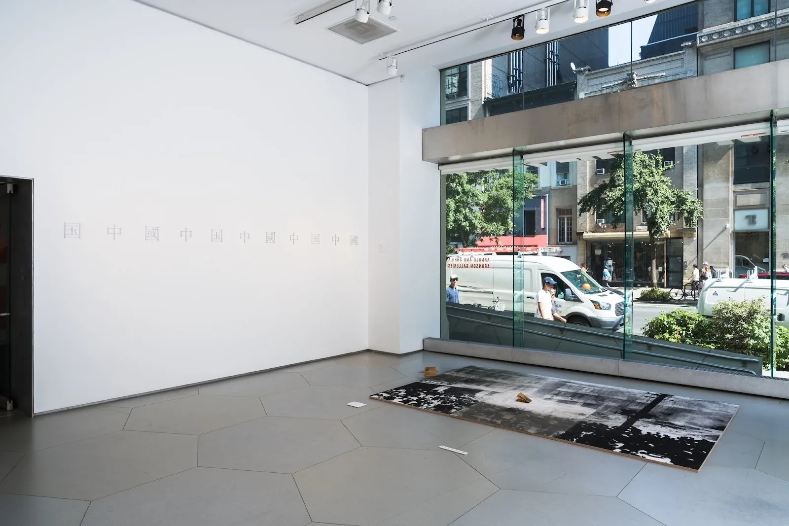 Parsons school of design thesis presentation gallery with large black-and-white photograph flat on floor and text installation country within a country by taiwanese artist ching-wei wang.