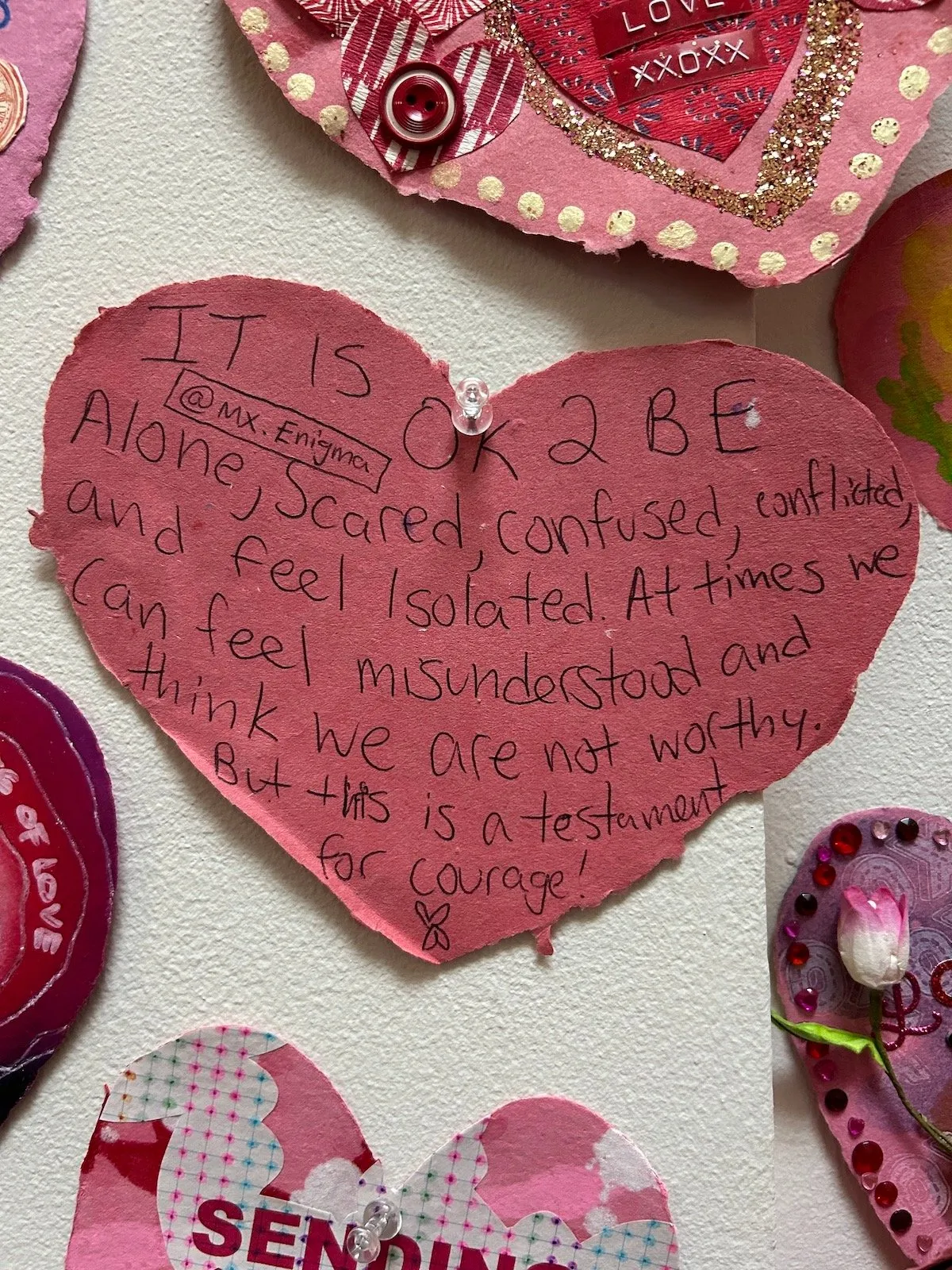 Pink heart-shaped Valentine's Day cards that reads it's okay to be alone scared confused conflicted and feel isolated. At times we can feel misunderstood and think we're not worthy but this is a testament for courage, moma ps1 love positive women.
