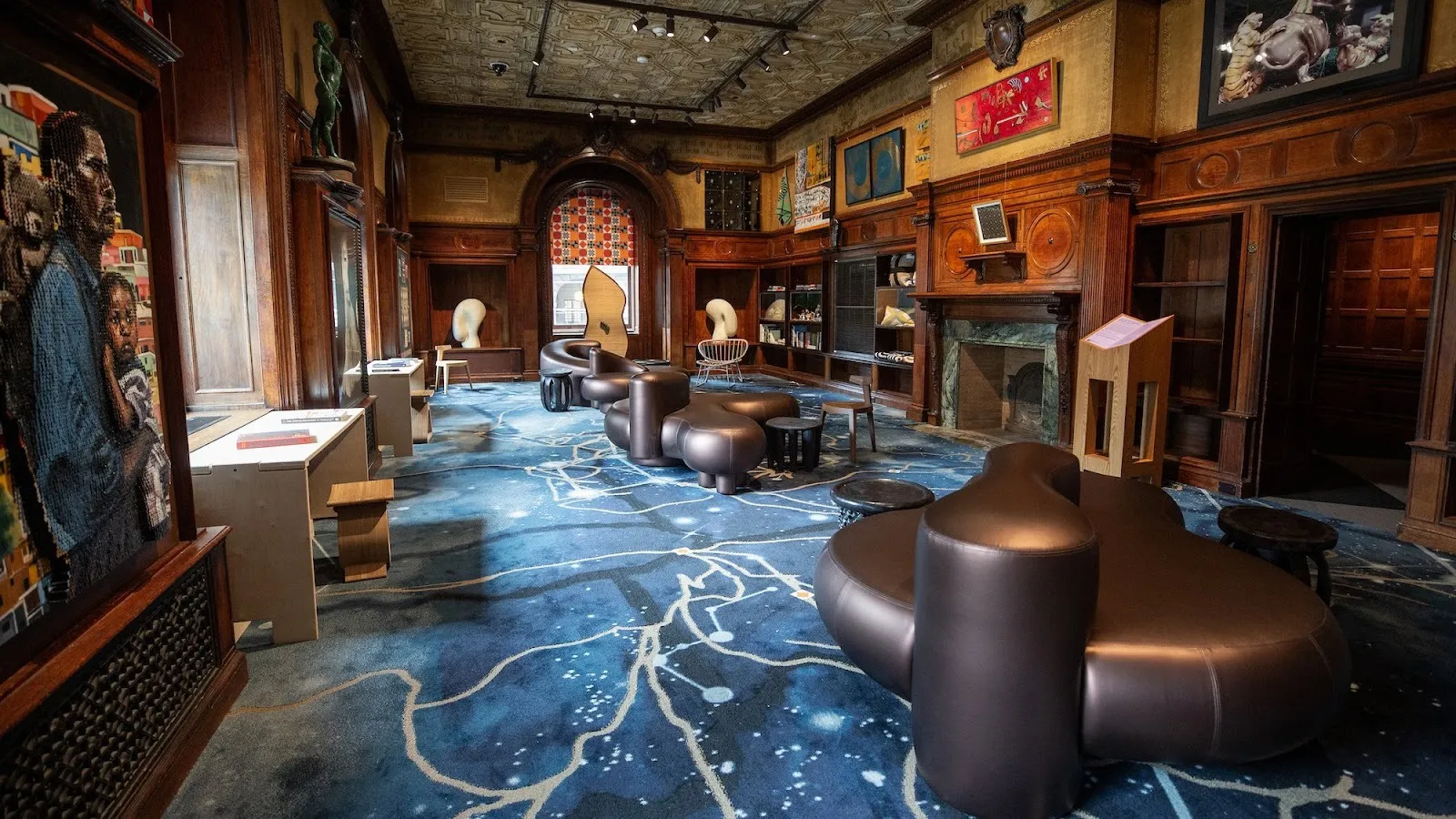 Georgian country style interior Library, with four sets of organically shaped circular black couch, walls decorated with black history memorabilia, texts and books on tables next to a couches with legal advice or about the Black diaspora.