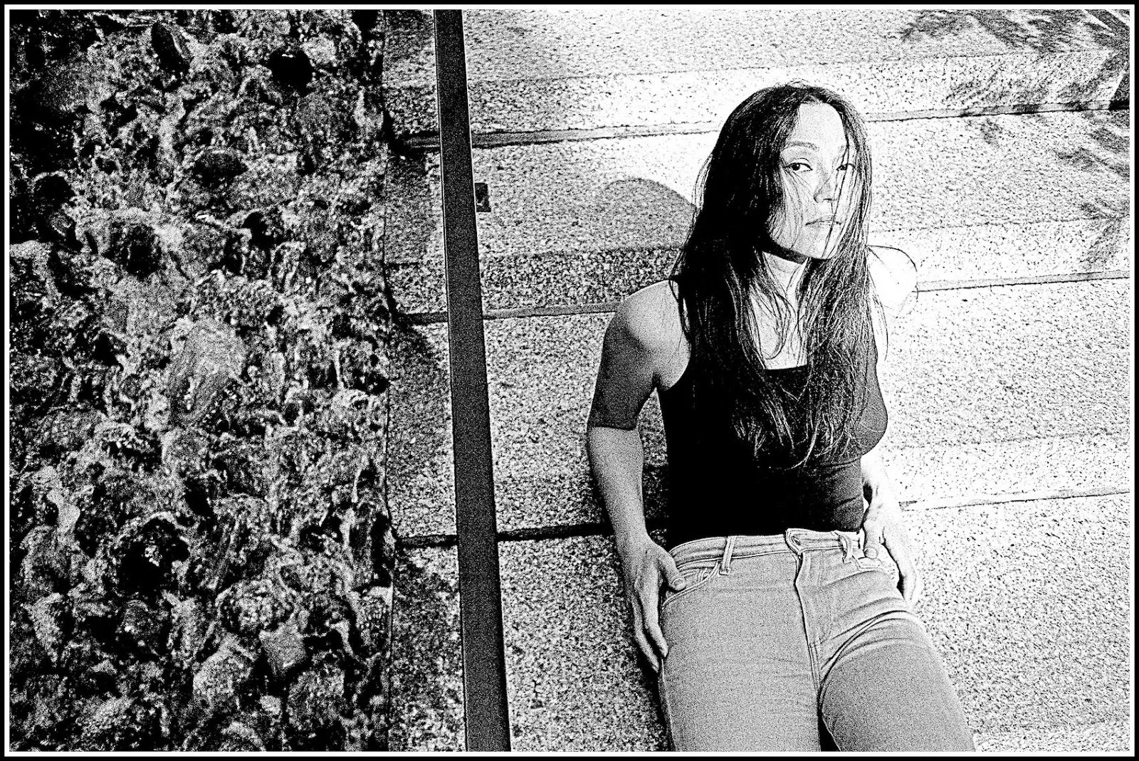 Black and white portraits of director and arthouse filmmaker isabel sandoval at greenacre park manhattan, she has long hair and is leaning against stairs next to plants, photograph by waltpaper.