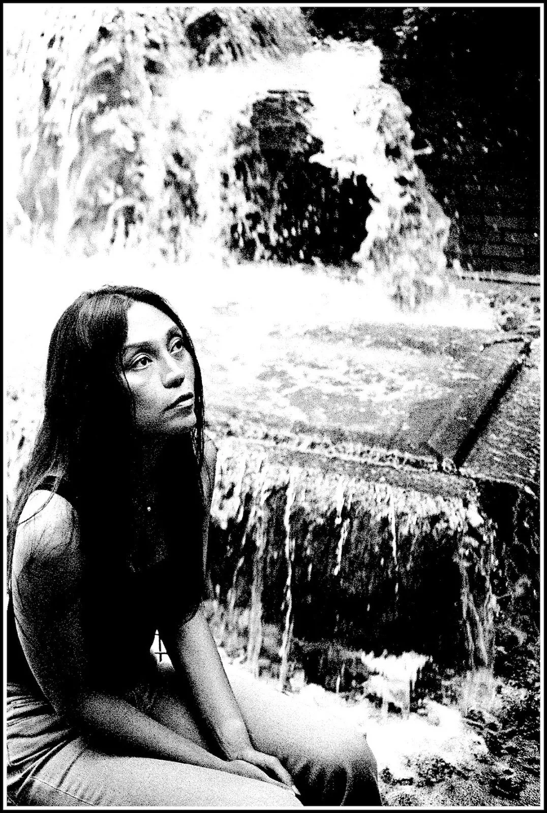 Black and white portrait of Filipino women and independent Art House filmmaker Isabel Sandoval, she has long hair sitting next to a fountain in greenacre park, Manhattan, photography by waltpaper.