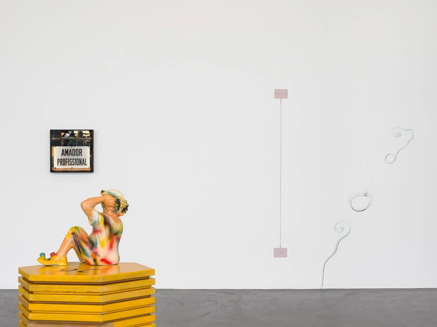 Yellow figurative sculpture of human leaning back on a pedestal, drawings on gallery wall and installation of amador professional at composicao, kunthalle zurich by ana jotta.
