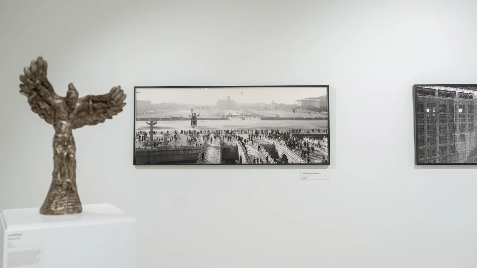Gallery room with black and white architectural photographs by Lois Conner on wall and figurative sculptures by liu shiming in two-person exhibition beijing stories.