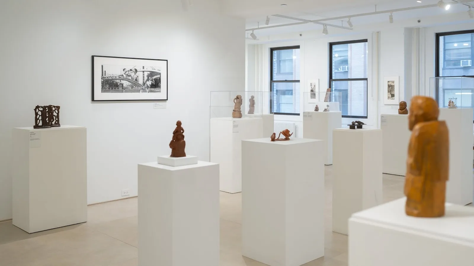 Gallery room with black and white architectural photographs by Lois Conner on wall and figurative sculptures by liu shiming in two-person exhibition beijing stories.