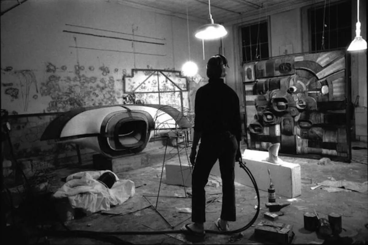 Black and white photograph of artist lee bontecou welding metal in her soho studio.