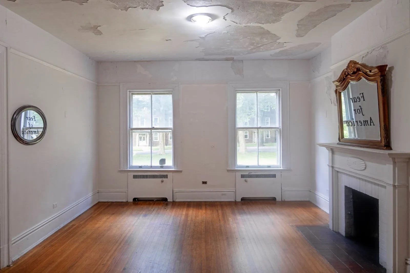 Room with wooden floor in which two mirrors are installed opposite each other, installation by bojan stojcic, in-between: fear of america, fear for america at residency unlimited, governors island.