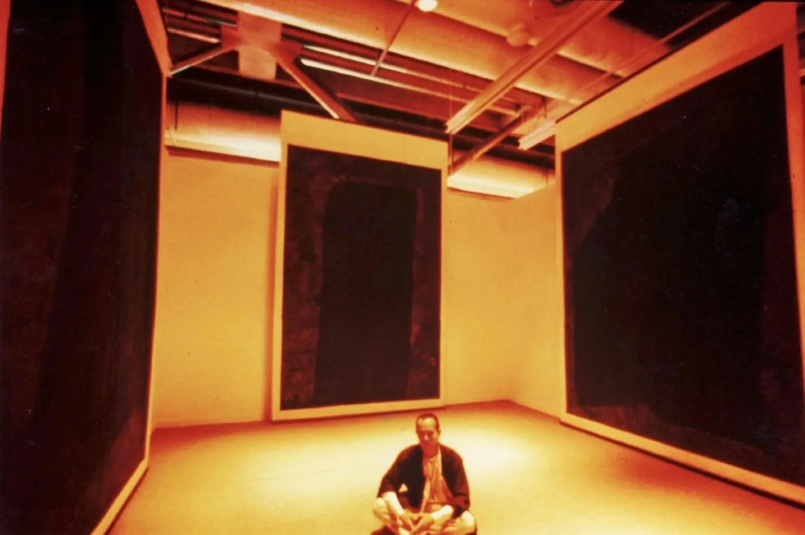 Artist Yang jiechang sits on the floor of exhibition space as part of magiciens de la terre in front of large-scale hanging scrolls, hundred layers of ink, ink drawing on xuan paper, at centre georges pompidou.