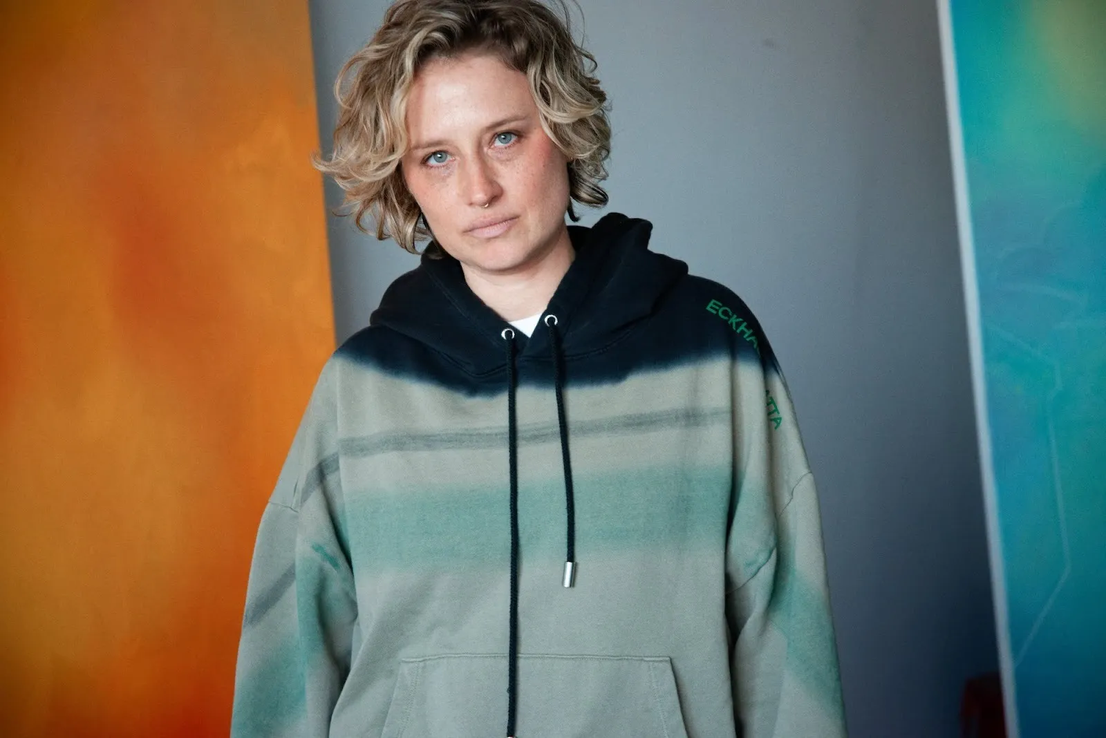 Artist Robin F. williams in front of orange and blue painting, ppow gallery artist studio portrait by curtis wallen.