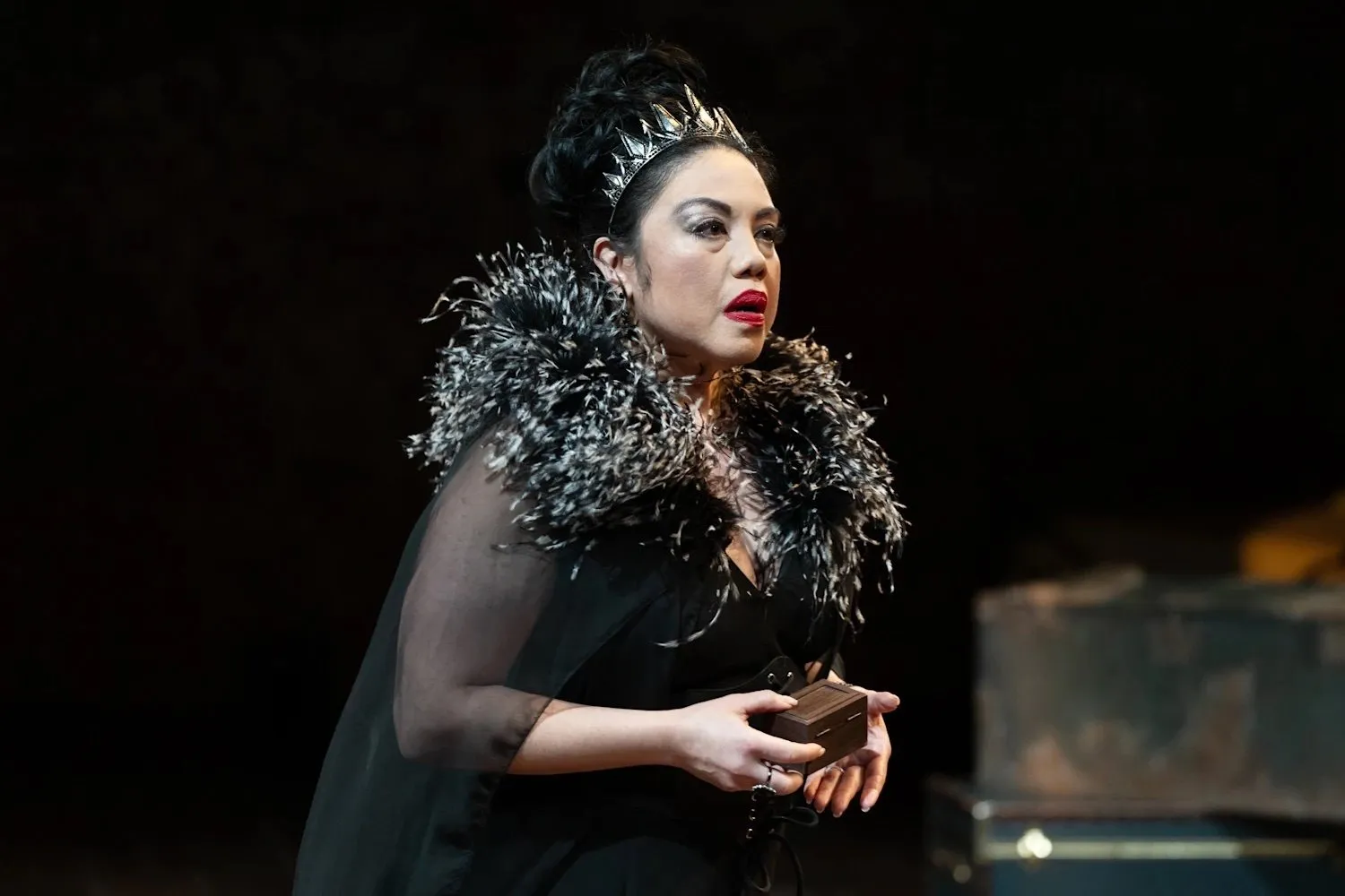 An actor in black gown stands on stage performing a gender-bending version of cymbeline at national asian american theater company.