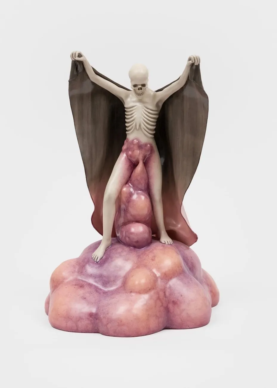 Shot of a figurative porcelain sculpture. A white, half-skeletal figure with raised arms looks down. The hands hold a fabric-like formation which blends into the base coming out of the body's genitalia: a bruised, bulbous, flesh-like mound.
