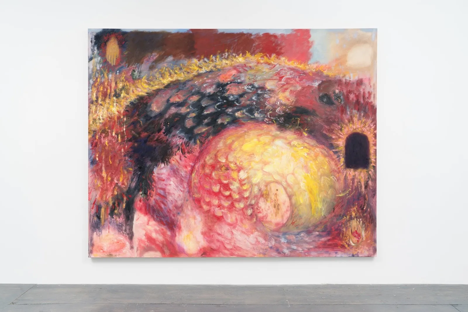 Installation shot of white gallery wall and grey flooring. Central and frontal is a large painting  of an abstracted, snake-like coiled figure. The painting is made up of reds, yellows, and deep blues, and features smaller abstracted objects.