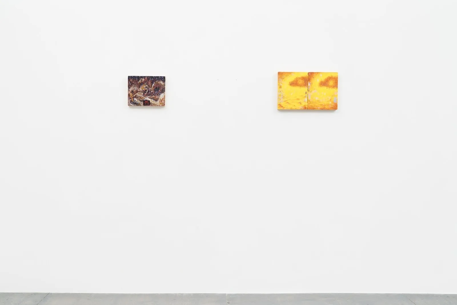 Installation shot of white galley wall. Two small paintings are hung slightly apart from each other. Right painting features two similar panels of orange and yellow. left painting features tans and browns.