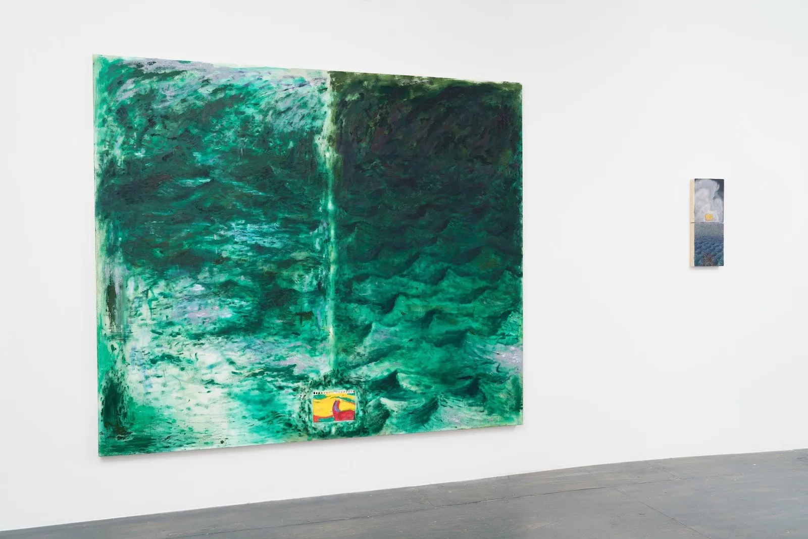 Installation view of white gallery wall and grey flooring. The left piece is large, landscape oriented, with turquoise and teal coloring and a small rectangle of yellow and red in the center bottom. The right painting is small and vertical.