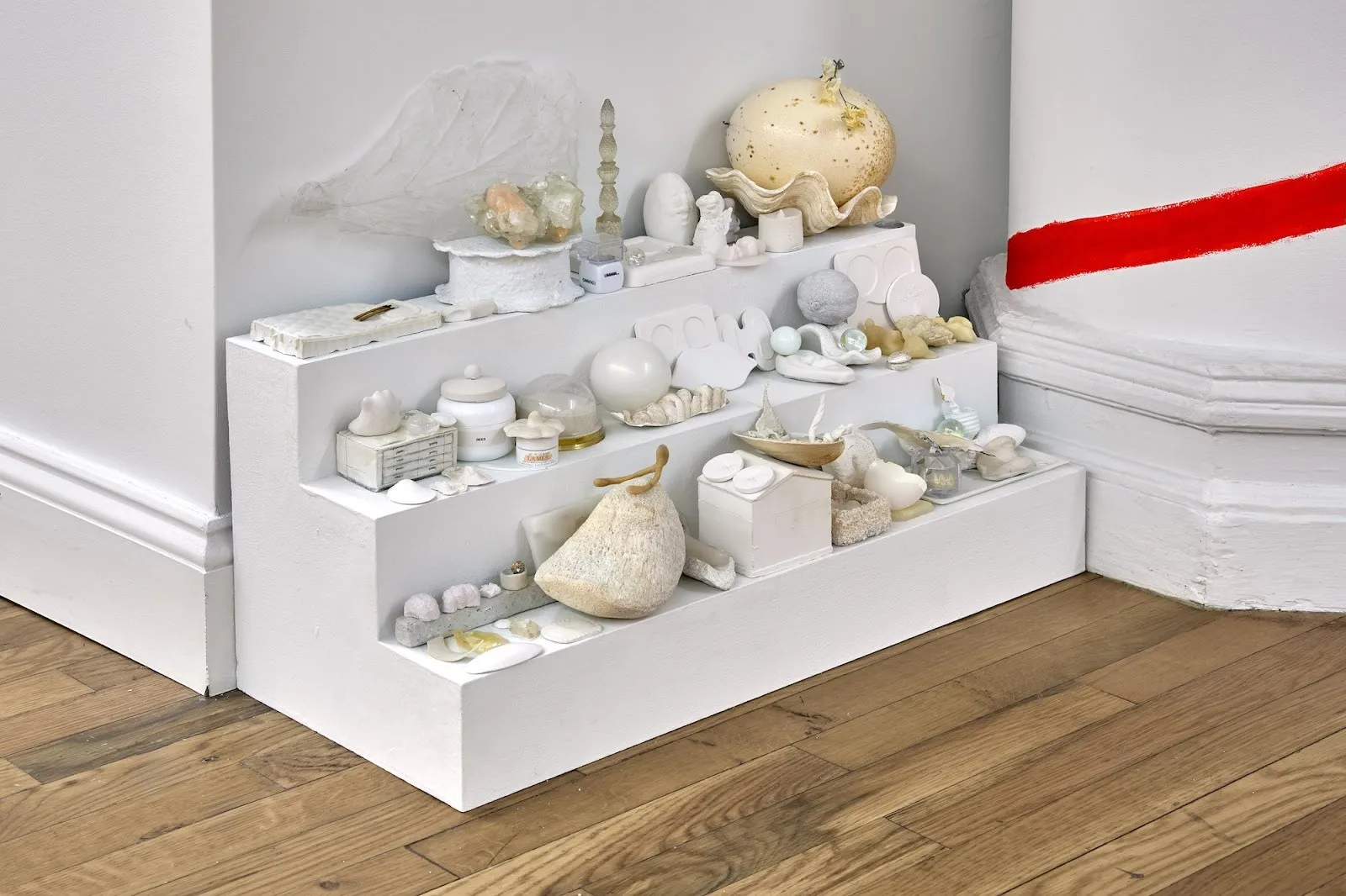 Collected white and beige objects like eggs, shells, and boxes arranged on white stairs, adam milner untitled, solo exhibition meanwhile at rainrain gallery.