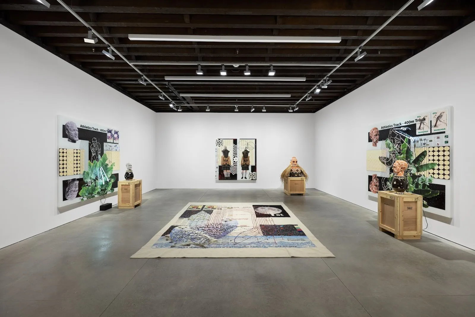 White cube gallery with collage works and wooden crates, textile peice lying in the middle of the floor, as well as sculptures evoking historical figures, tavares strachan starless midnight marian goodman gallery.