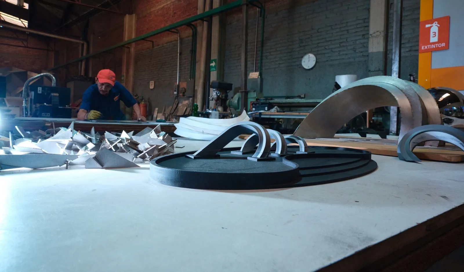 Fabrication photo of strata work in progress with miniature model on a workshop desk, public installation by omer yosef and adrian yu in front of mesa city hall.