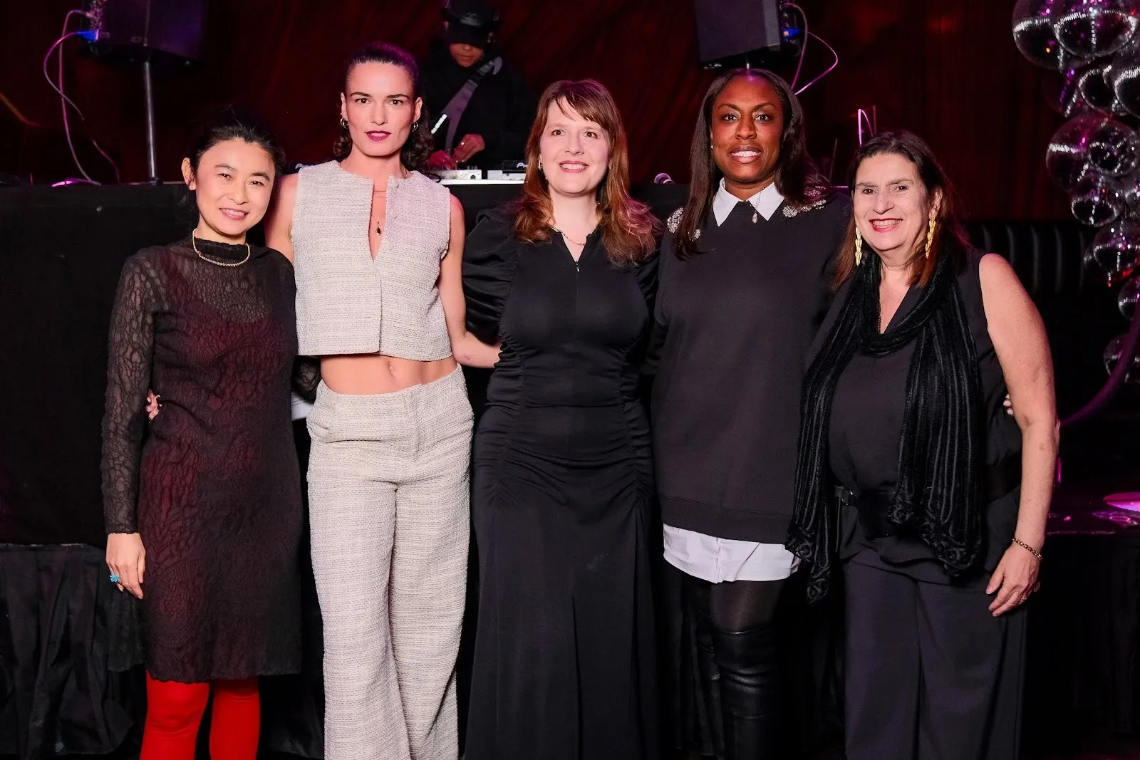 Five people pose for a picture in front of a DJ booth.