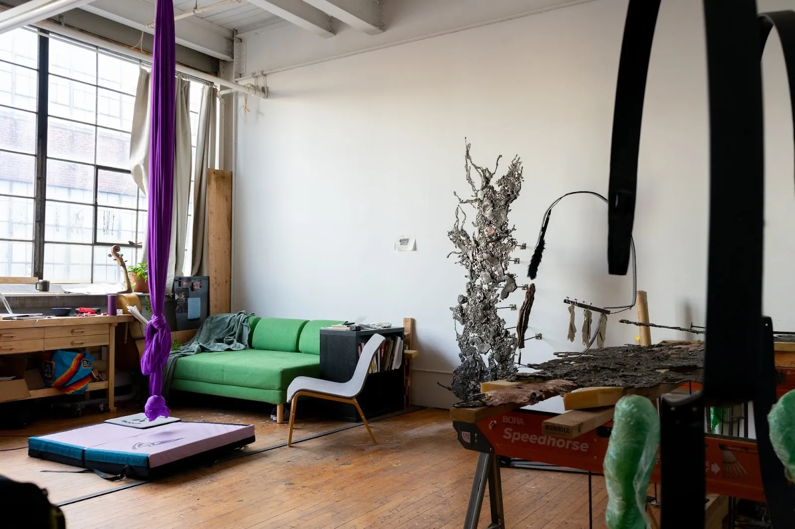 Elli Fotopoulou’s studio in New Haven, Connecticut, purple aerial silk next to green couch next to steel sculptures.