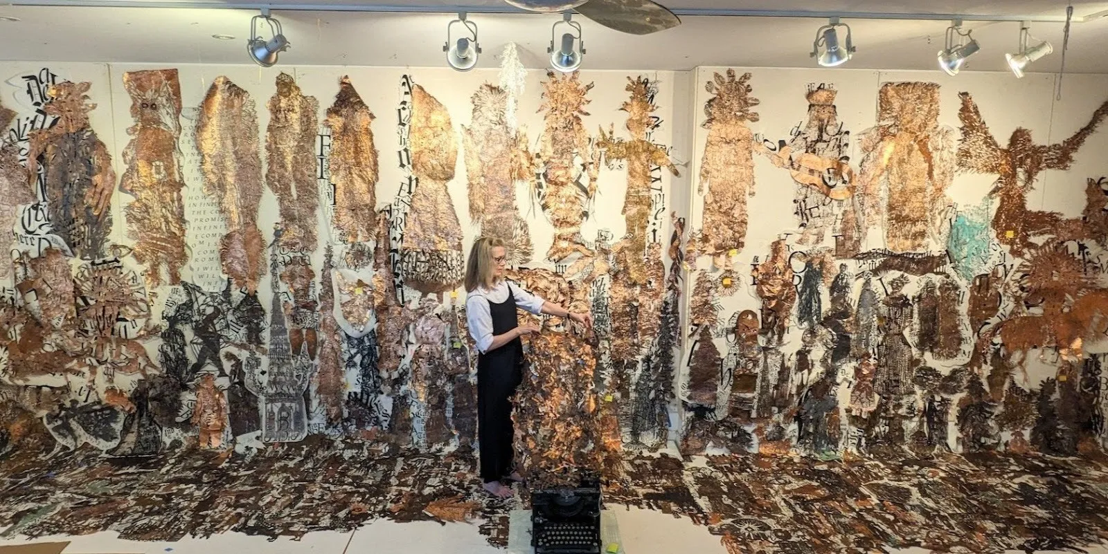 Lesley dill in front of ongoing project created with copper foils inspired by emily dickinson poems.