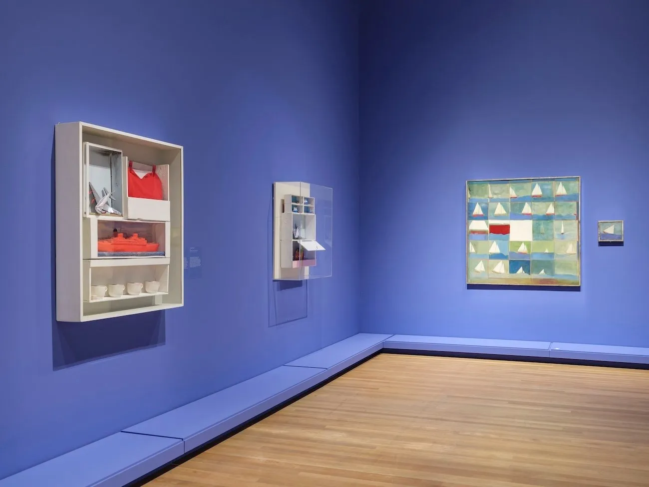 Blue walls with installation cabinets including textile and colored geometric shapes, Exhibition view of canadian artist joyce wieland heart on retrospective at the national gallery of canada, mmfa.