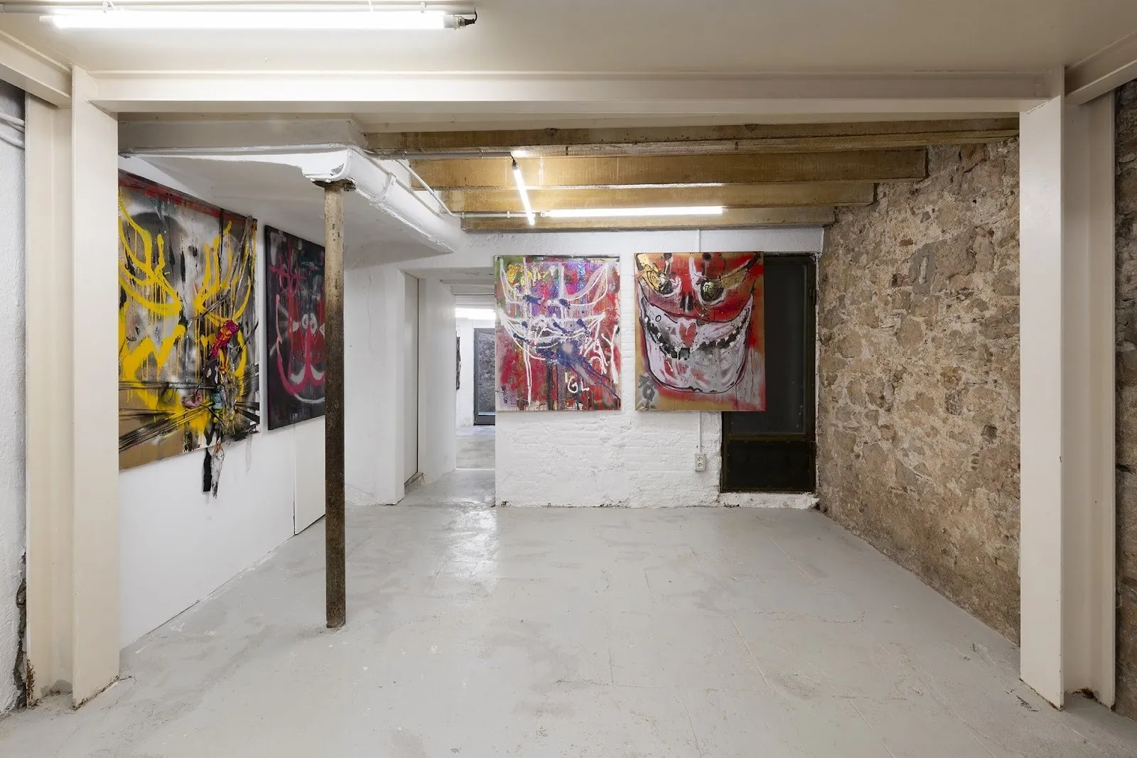 Gallery space with exposed wooden beams and brick wall, abstract gestural paintings hang on the walls, arca, angels at cordova gallery barcelona.