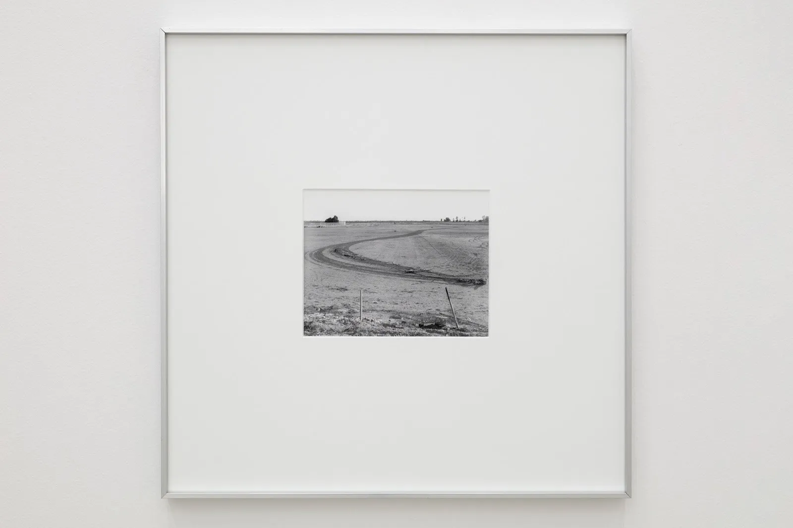 Square metal framed small black and white photograph. The photo shows a dirt path winding through a rural landscape.
