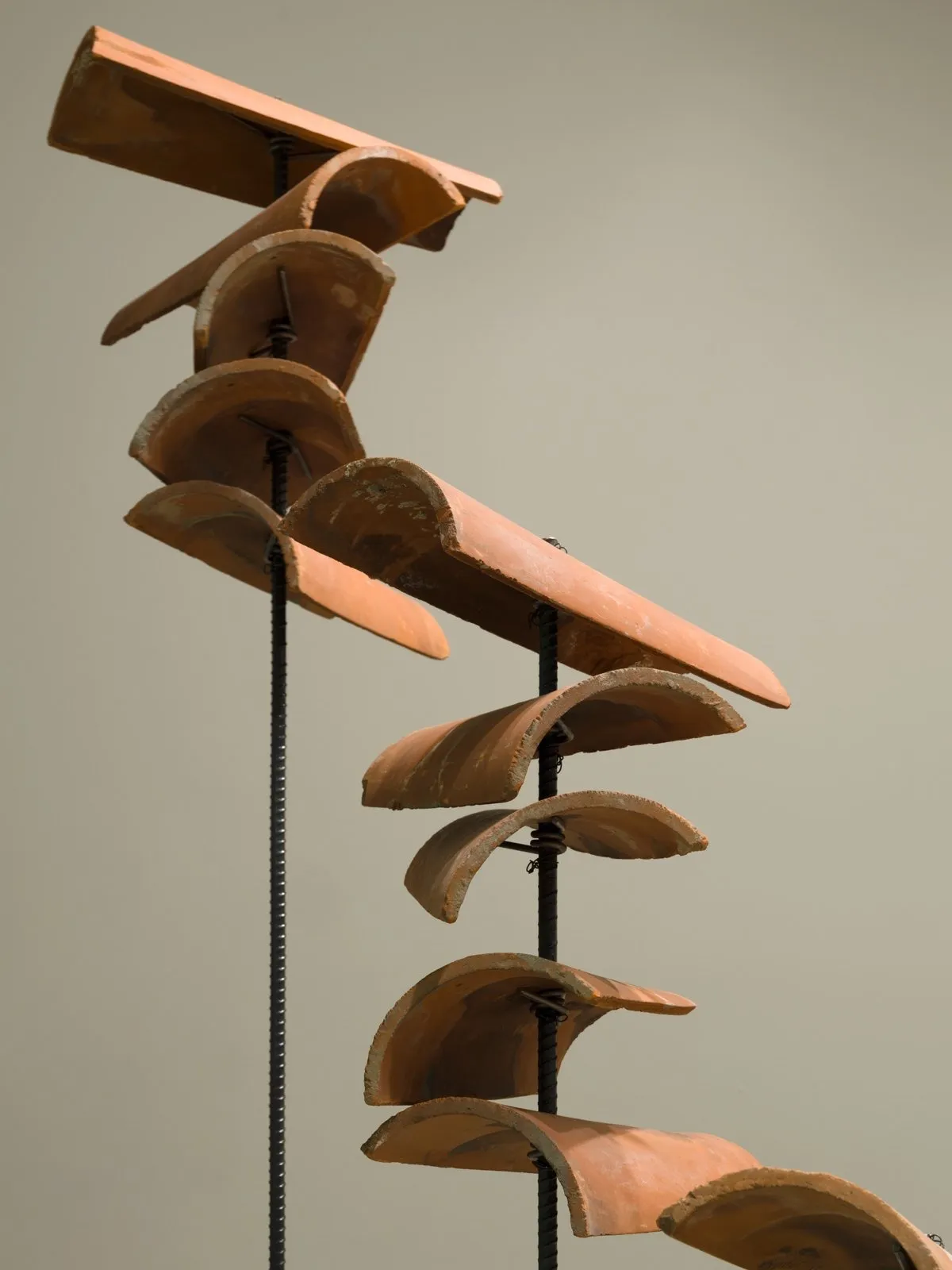 A sculpture made of rebars that pierce loos stacks of terracotta roof tiles.