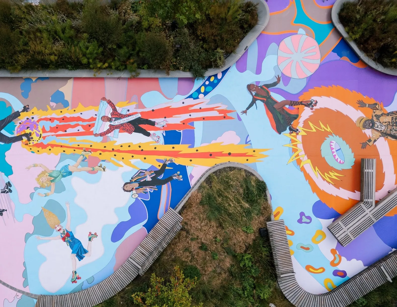 An aerial shot shows the floor of an outdoor space covered completely with colorful illustrations of people and patterns.