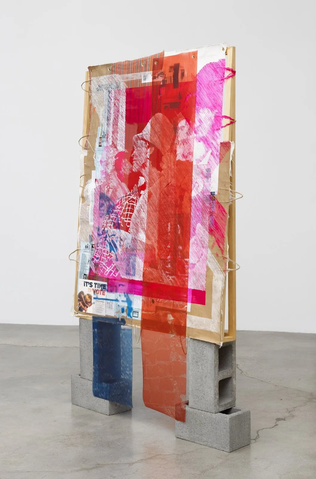 Colorful print incorporating pink and blue stripes on top of archival photographs is mounted on wooden frame and poised on bricks to form ecology of fear installation, artist tomashi jackson.