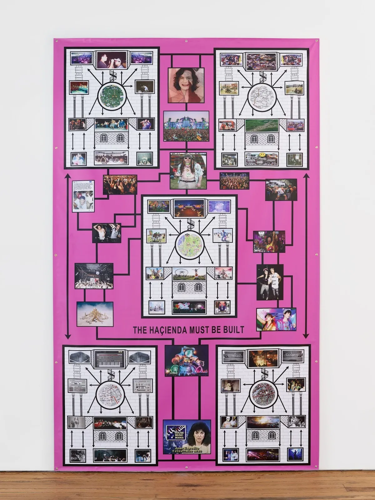 A large 2D work mounted to a white wall is comprised of a pink background with collaged images from pop culture grouped in various boxes and connected by a flow of black arrows, creating a diagrammatic composition.