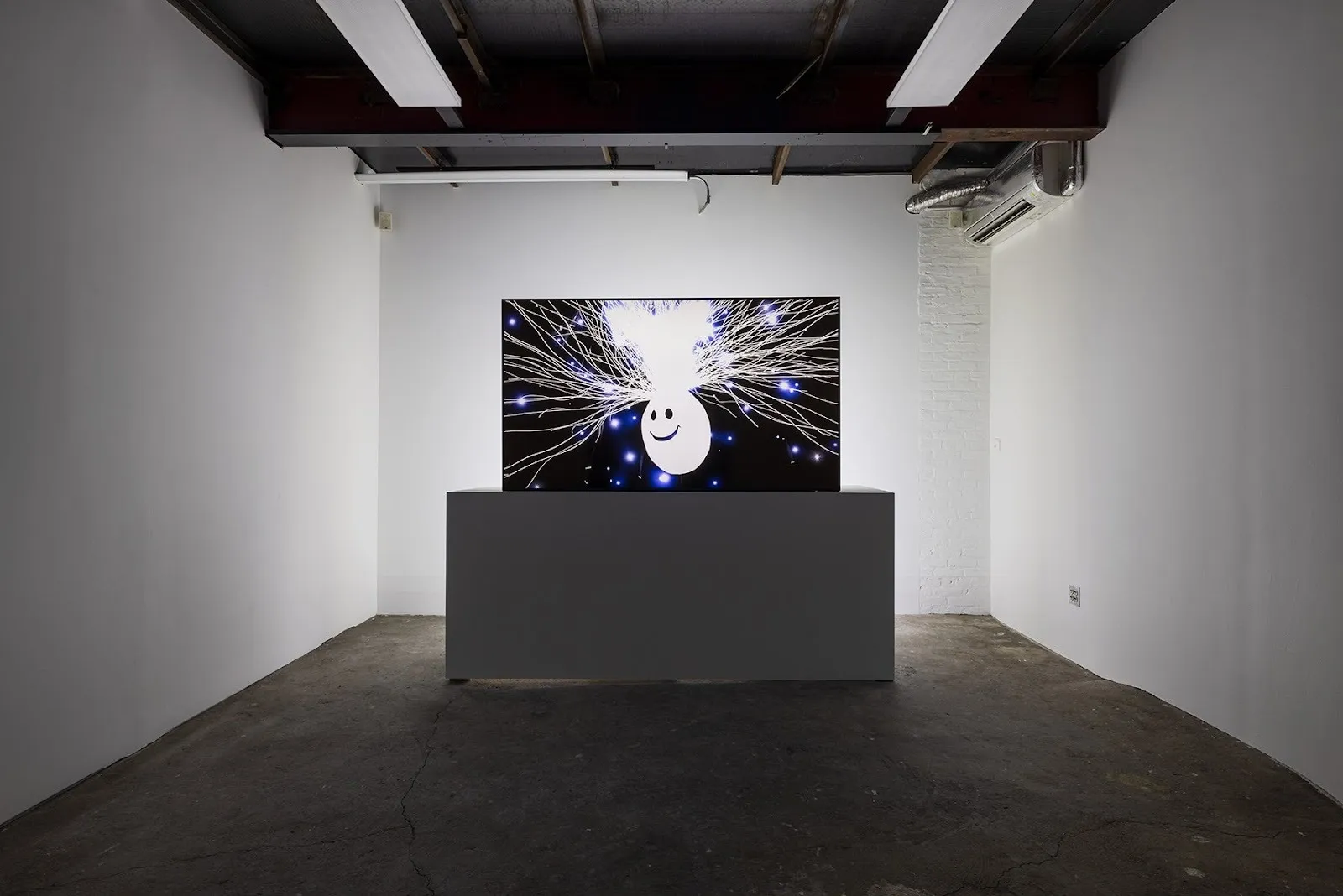 Grey gallery room with tv monitor screening a video of stress ball emitting electrifying waves, Gregory Kalliche, Anvil (2025). 4K video with sound, 9-channel lighting program, DMX controllers, lighting interface.