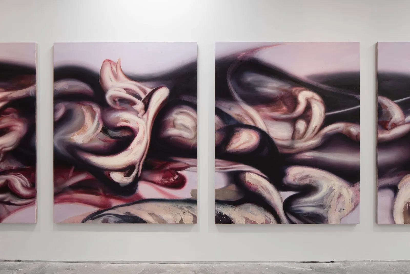 Three abstract paintings with fleshy, swirling forms in pink, mauve, and black tones mounted on a white gallery wall.