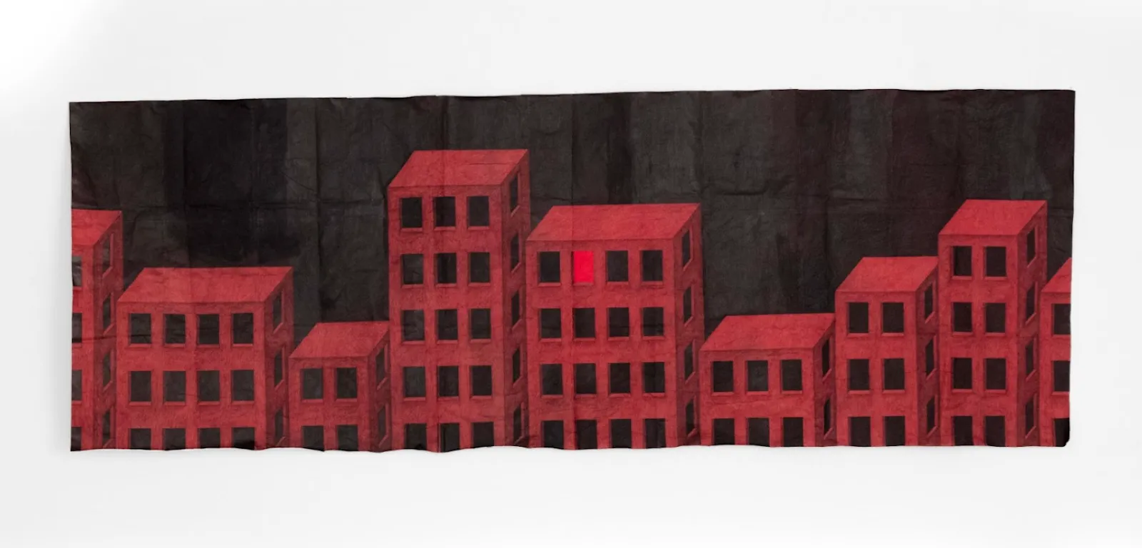 A work on paper depicts apartment or office-like buildings rendered in red. All windows are black except for one, illuminated in a bright red. The background is black. The piece has fold marks and creases.