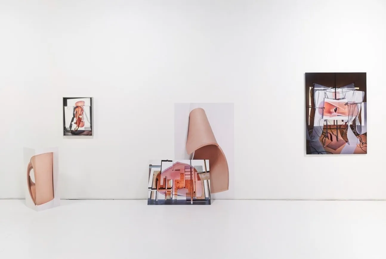 Contemporary art installation with abstract photographs and cutout shapes on a white wall and floor.