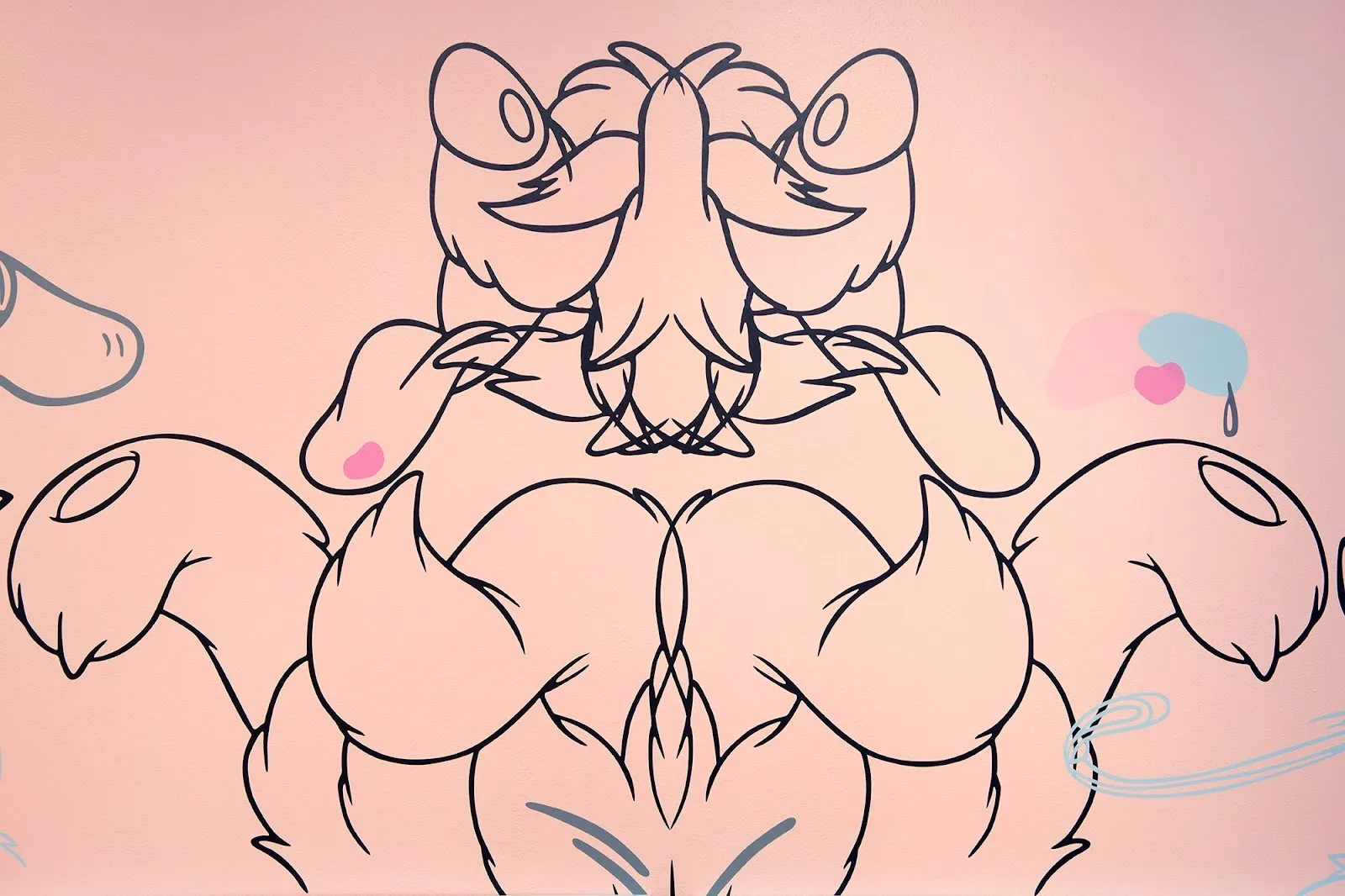 Painted directly onto a pink wall, thick black lines create a cartoonish but symmetrical, abstracted object. The object is two halves, mirrored, and has no discernible traits except for the suggestion of fur.