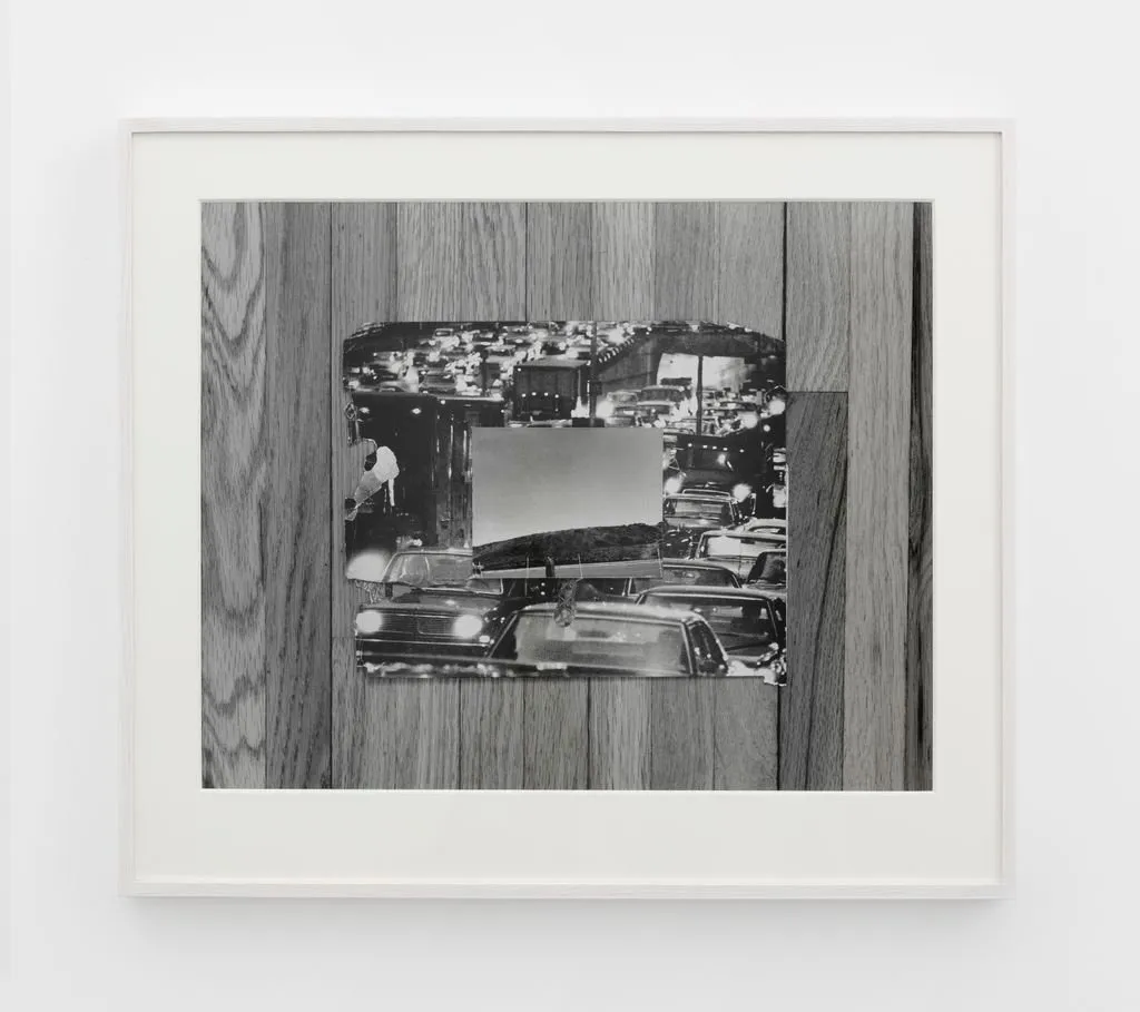 A white-framed photograph mounted to a wall features a black-and-white collage of wood panels, an image of a car, and a landscape.