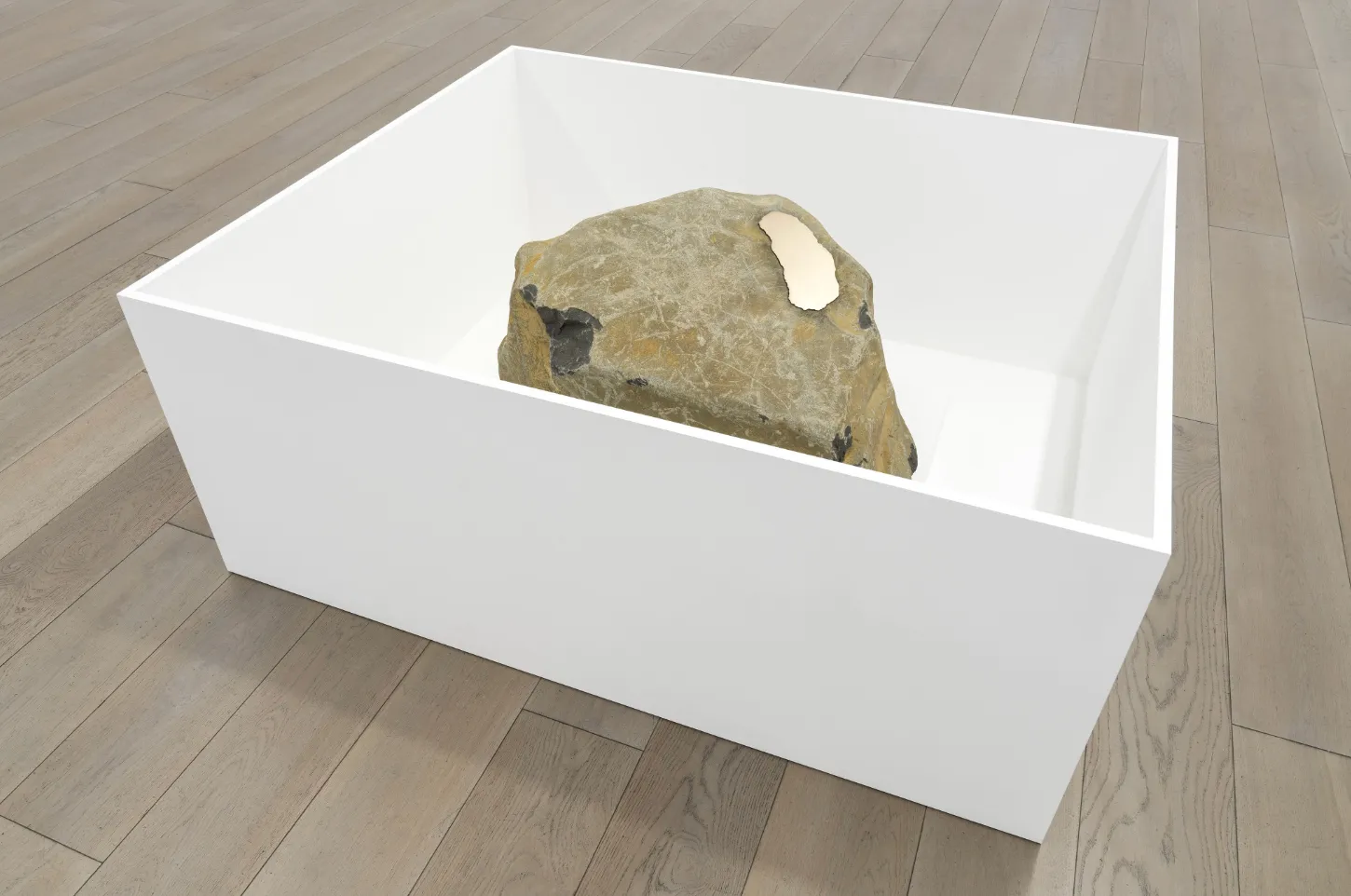 Sitting on a hardwood floor, an open wooden white box contains a boulder with a piece of shiny metal affixed to the surface.