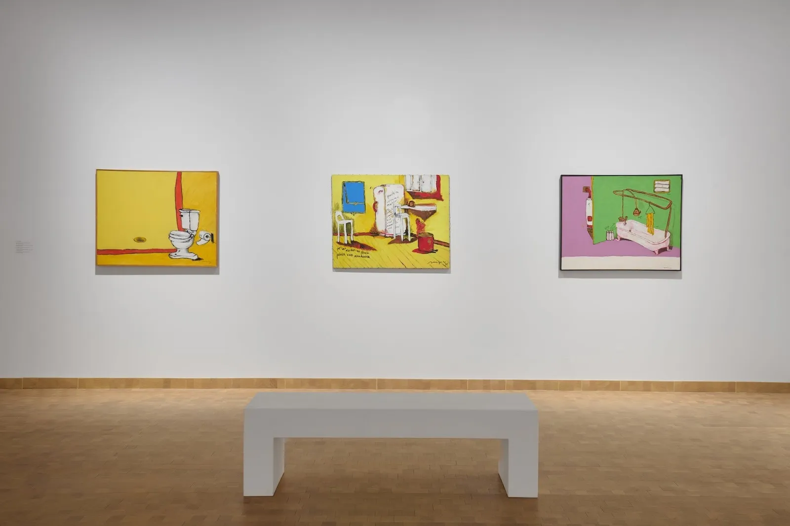 Gallery view with three vibrant paintings on a white wall; each depicts domestic bathroom interiors with bold, cartoon-like colors and simplified objects.
