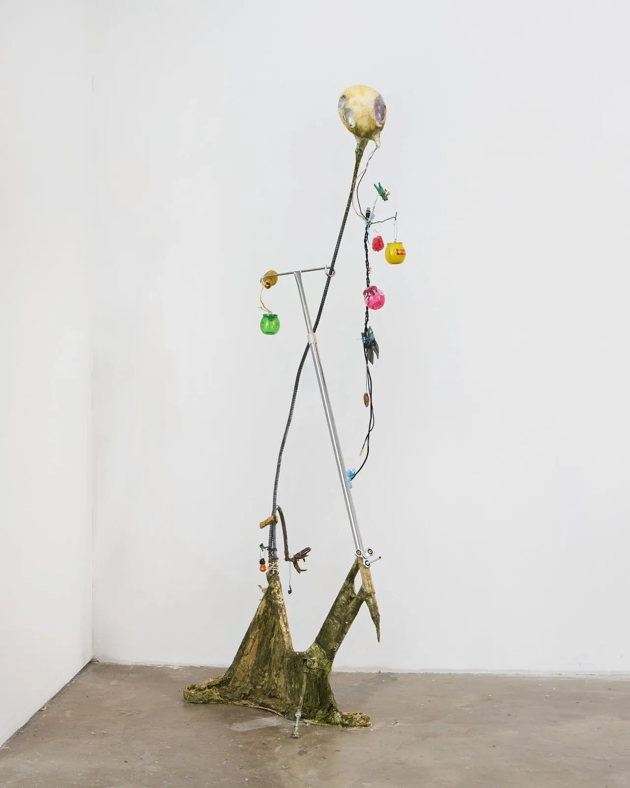 A sculpture made from composite found objects features part such as an IV pole, empty BuzzBallz, and cables.