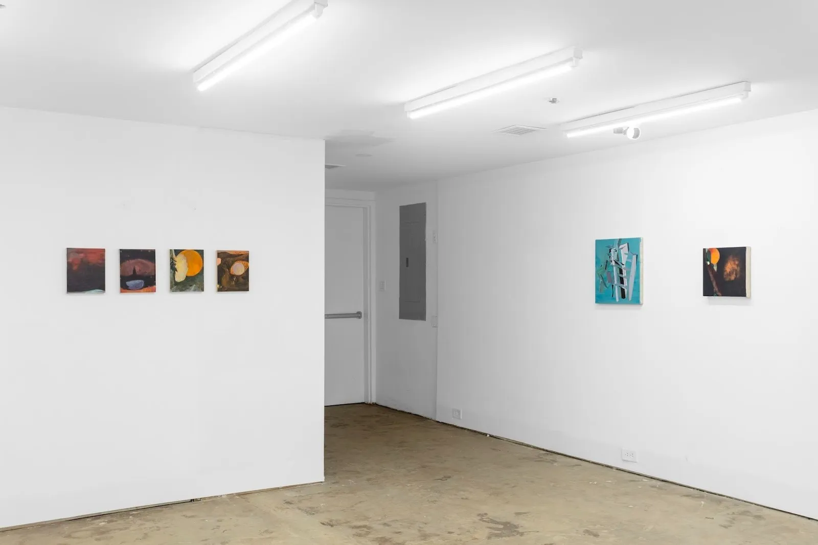 A corner gallery view with a row of four small paintings on one wall and two mid-sized abstract works on the adjacent wall.