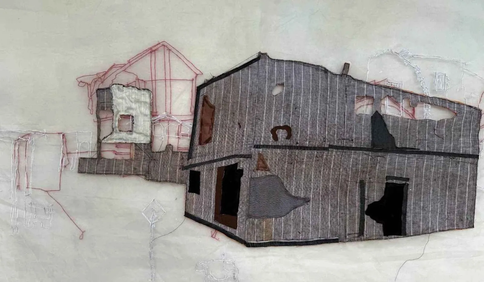 A textile artwork depicting fragmented house structures outlined and stitched with layered fabrics and thread on a pale background.
