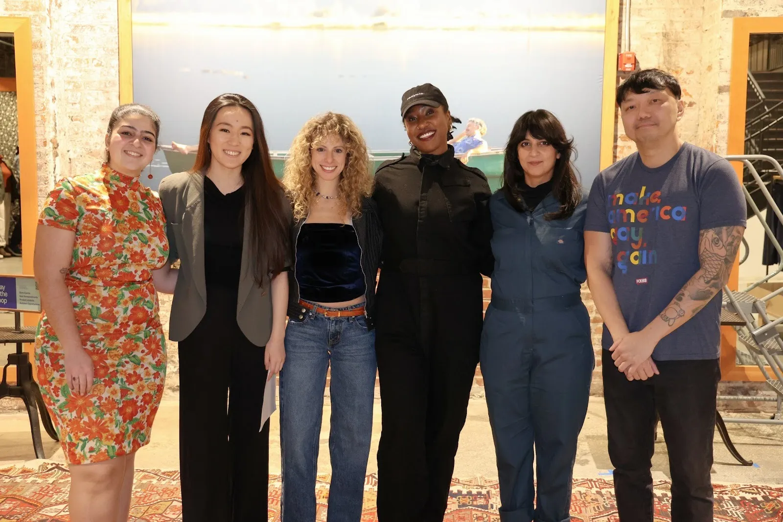 Six people stand together in a clothing store, smiling and posing for a photo.