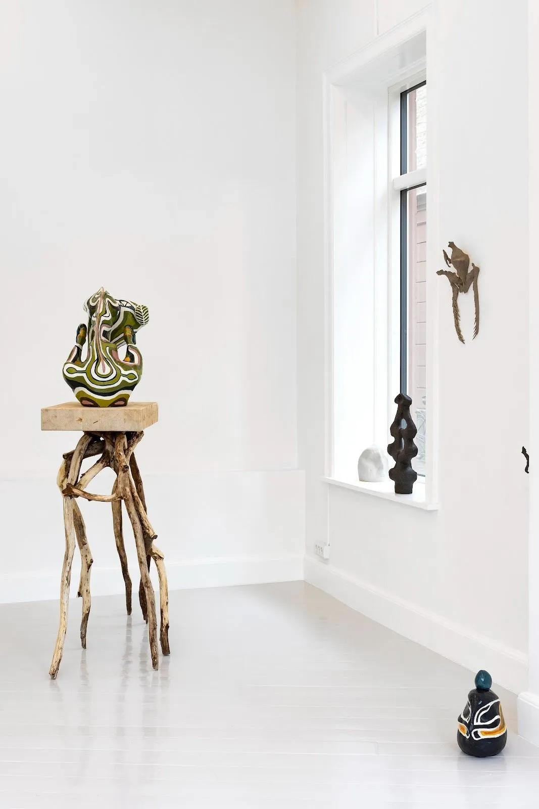 Several sculptural works populate the walls and floor space of a gallery. The rest on windowsills, plinths, and walls. Each echo organic forms.