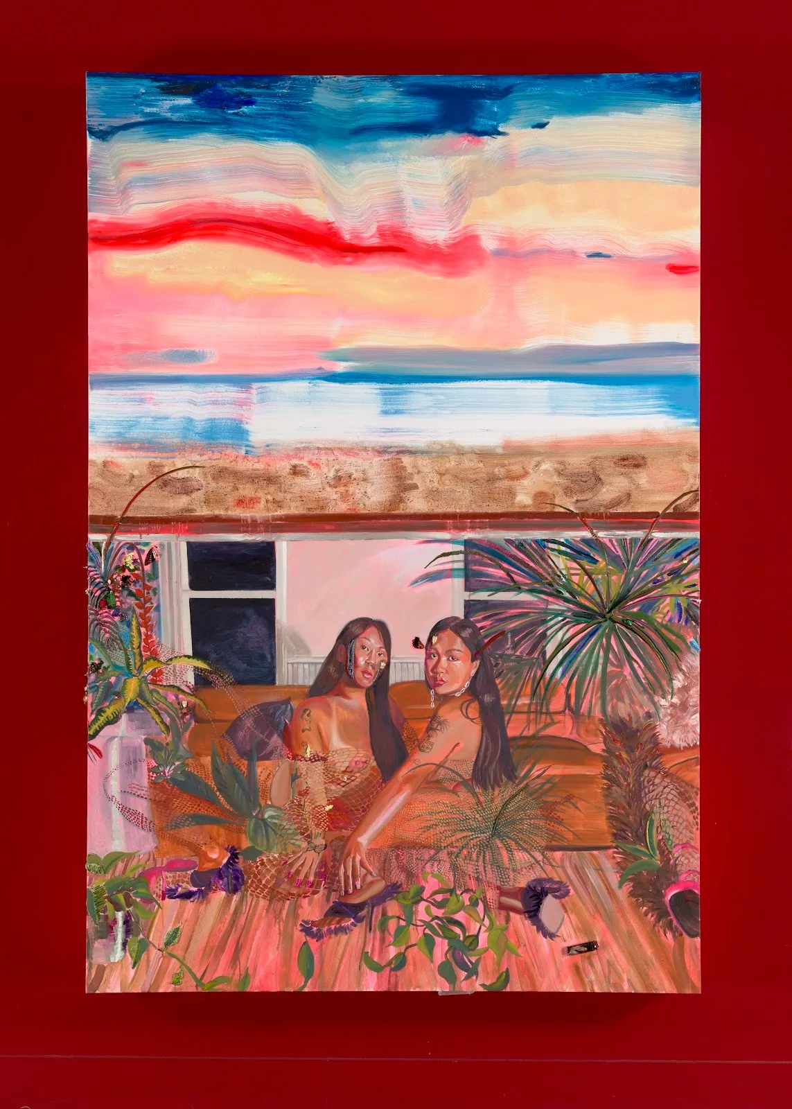 Against a red wall, two figures with long hair sit on a couch and look directly at the viewer. They are surrounded by plants and foliage. In the background, a house and an ocean against a sunset sky dominate the top half of the painting.