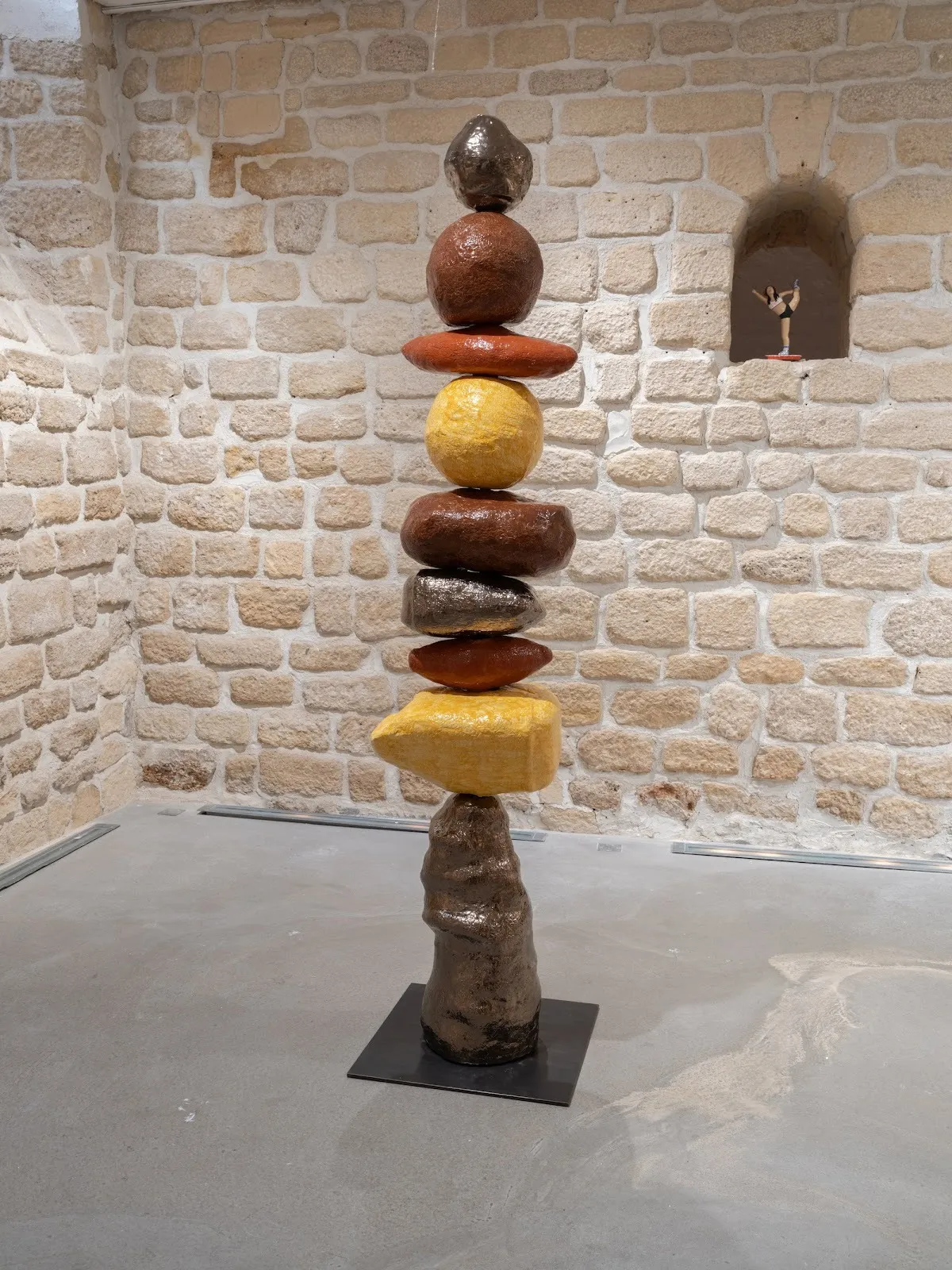 A tall stacked sculpture of rounded, earth-toned forms resembling stones balanced atop each other.
