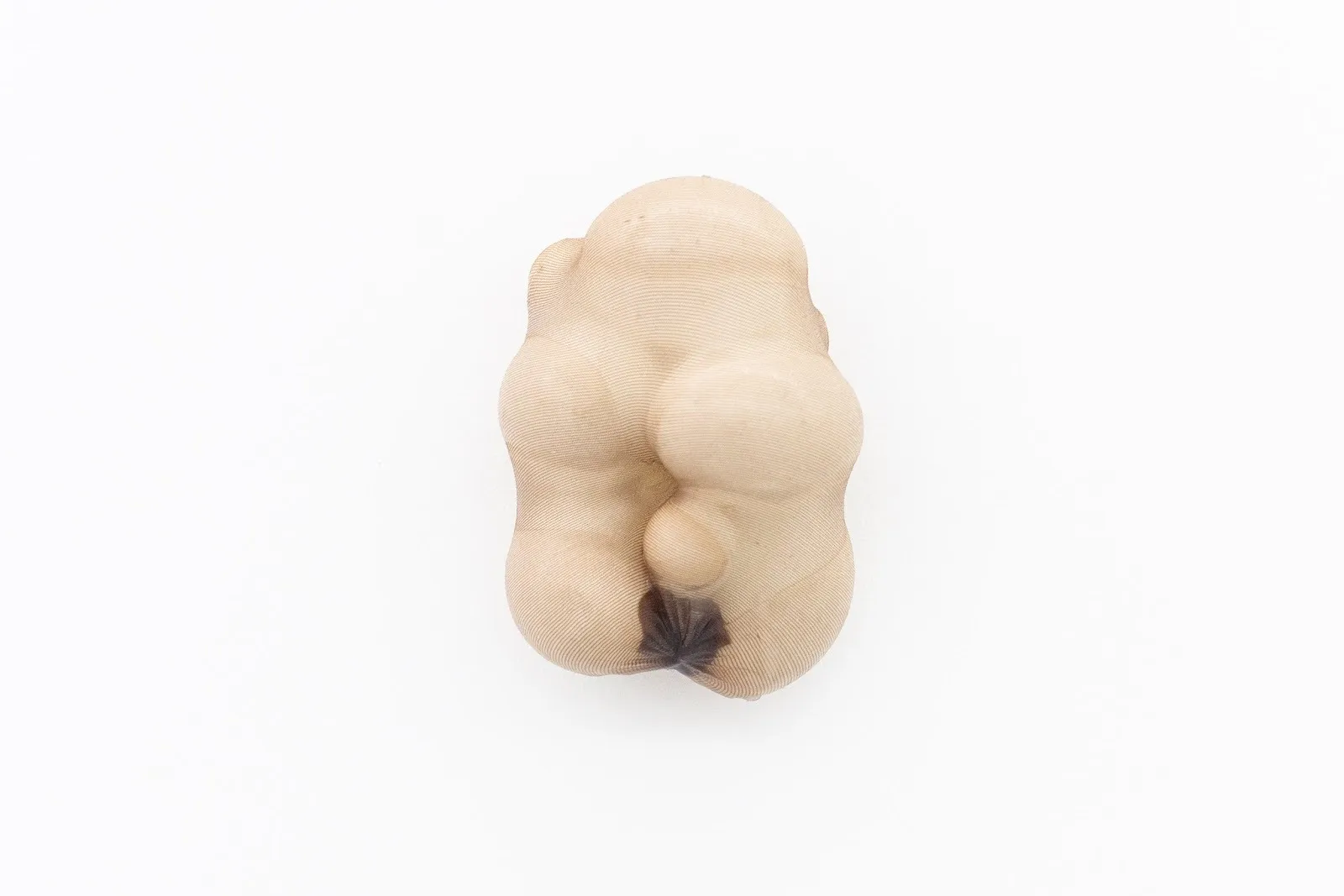 Organic, flesh-toned sculpture resembling a soft, bulbous form covered in sheer fabric.