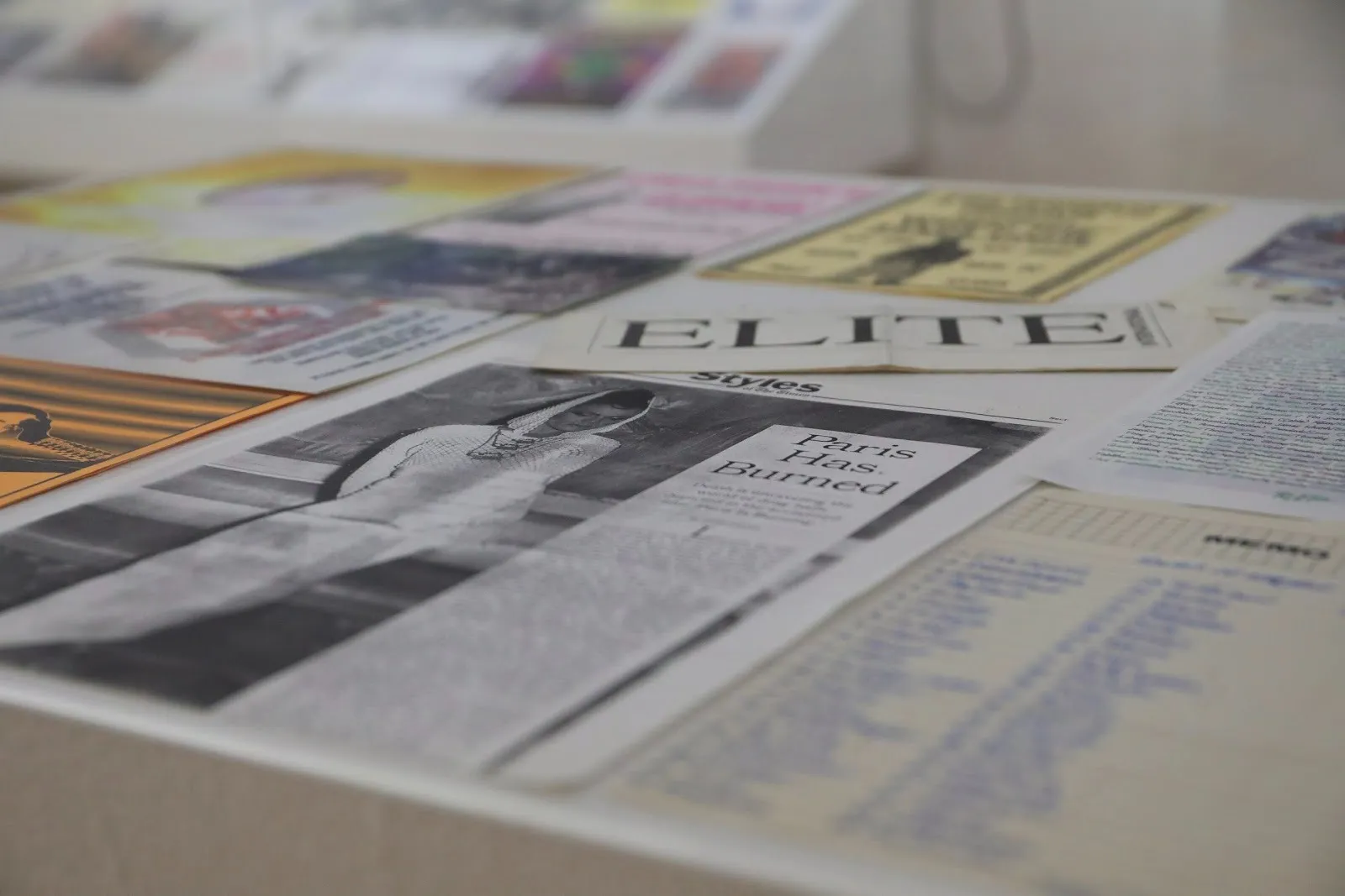 Close-up shot of various paper ephemera, comprised of magazine and newspaper cutouts. A prominent piece reads "ELITE" in all caps.