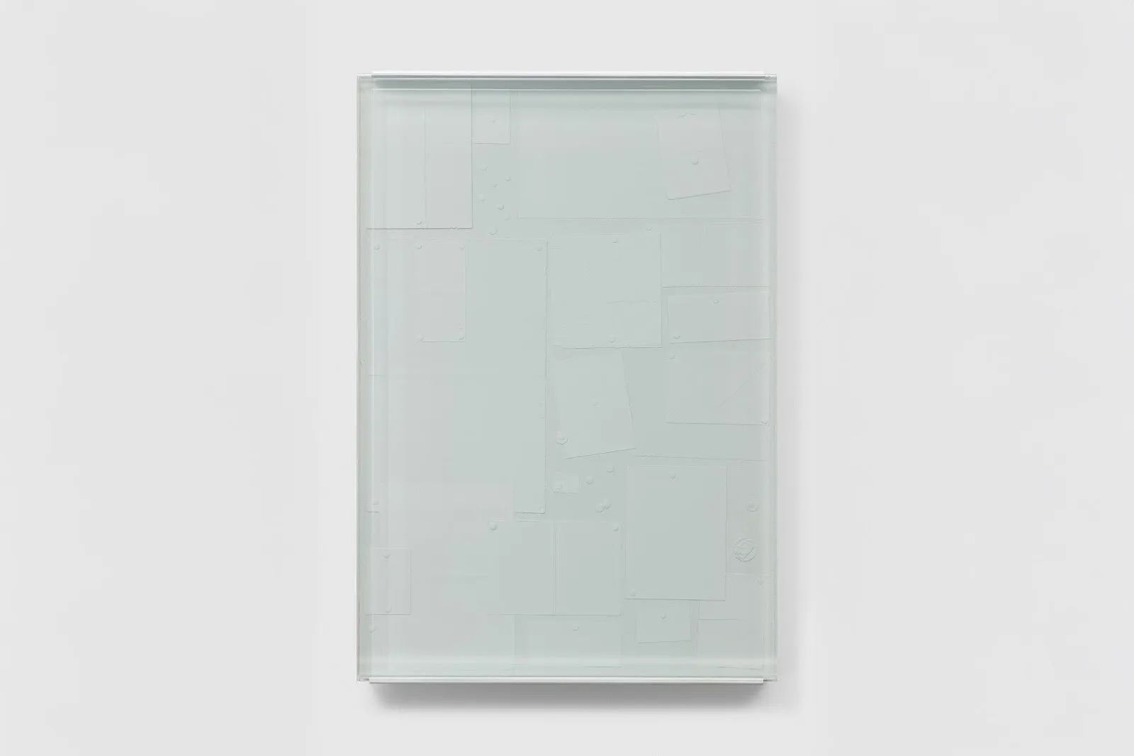A resin panel appears as a sheet of glass with a bluish-grey tint. Inside the resin, various sized pieces of cut, blank paper are loosely arranged.