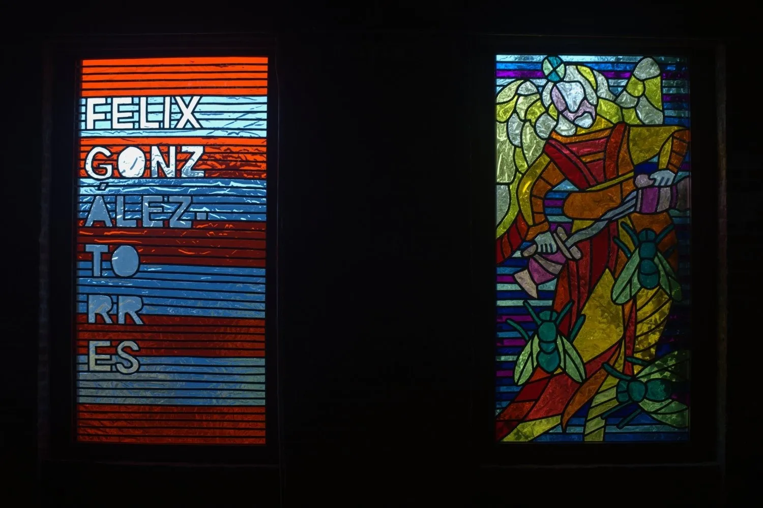 Two stained glass windows depict red and blue stripes with the words "FELIX GONZALEZ TORRES" (left), and faceless, saintlike angel figure holding a sword and surrounded by large flies (right).